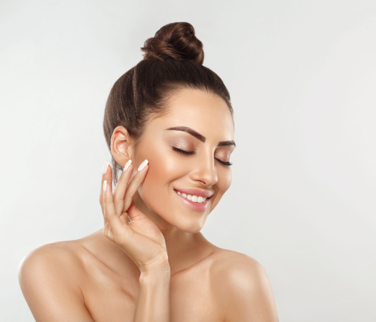 Beautiful young woman with clean perfect skin. Portrait of beauty model with natural nude make up and touching her face. Spa, skincare and wellness. Close up