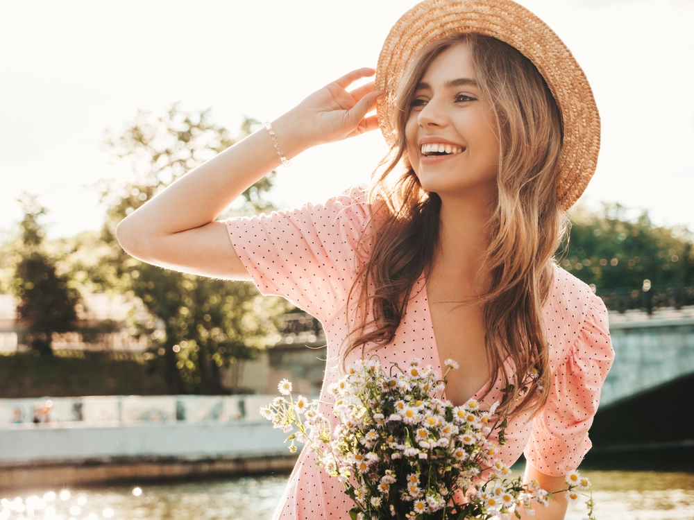 middle aged woman with beautiful smooth facial skin while outside holding flowers and smiling